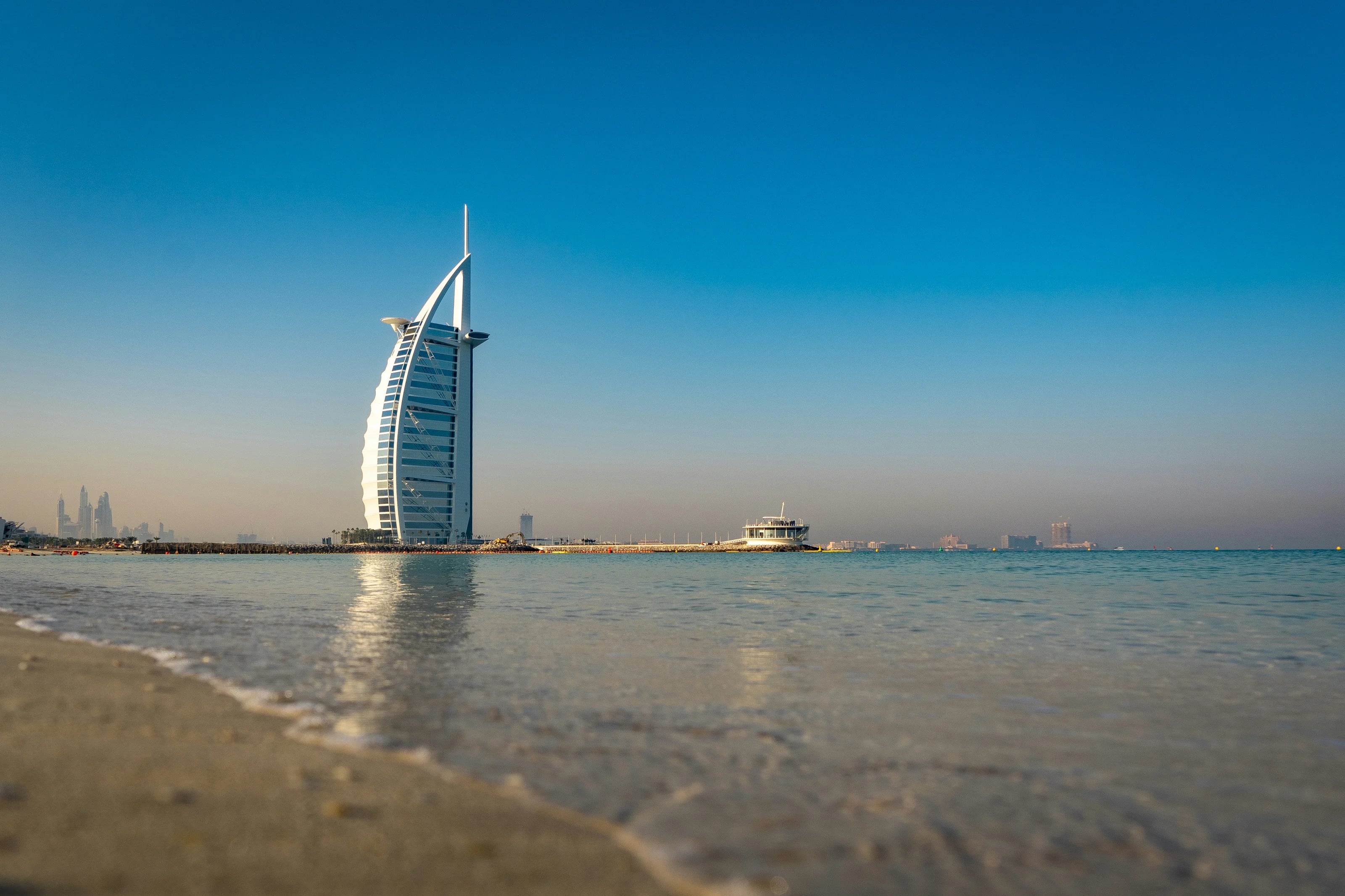 Burj Al Arab seen from the beach across calm water in Dubai