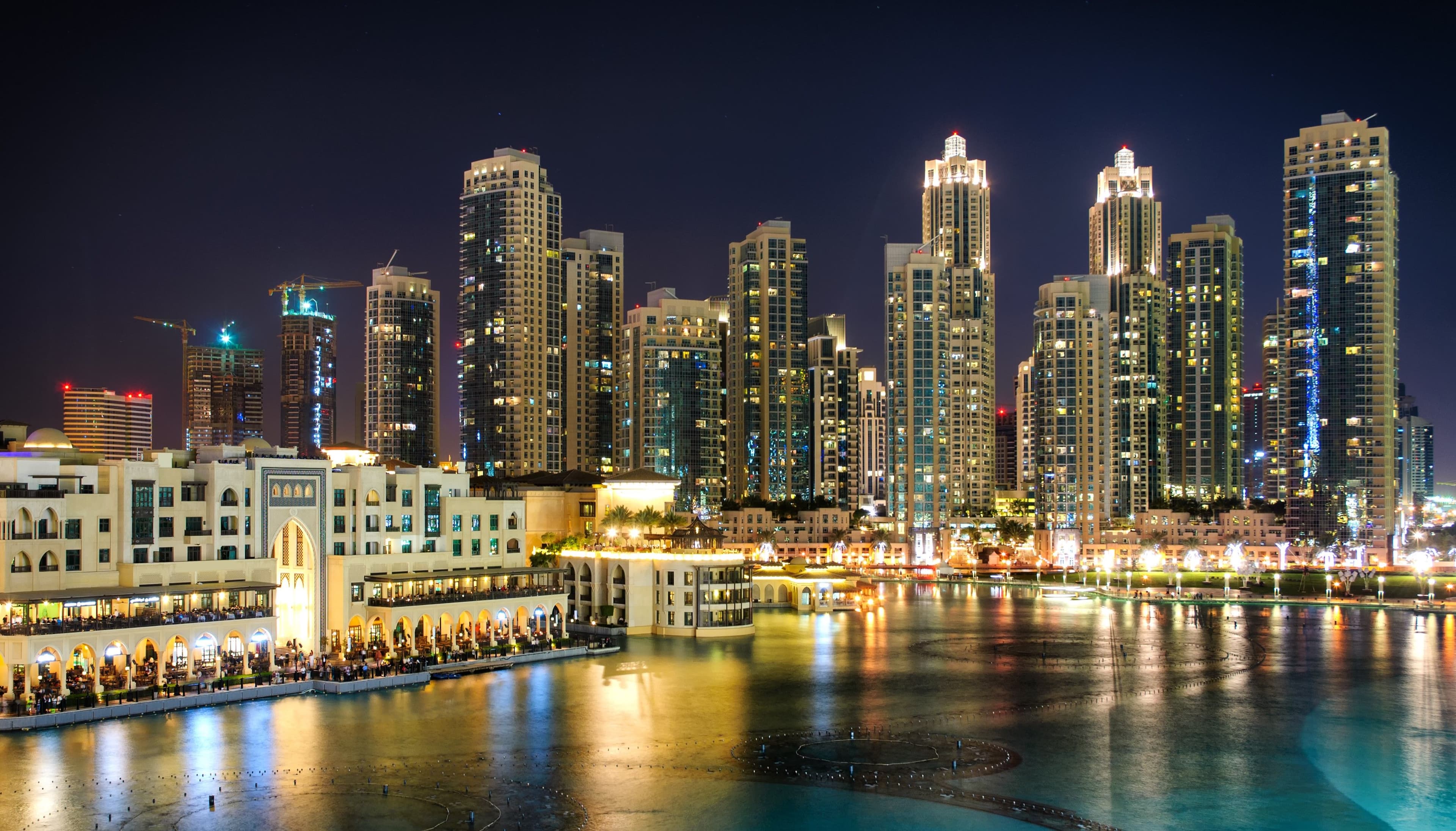 Dubai downtown skyline at night with illuminated skyscrapers and waterfront reflecting city lights